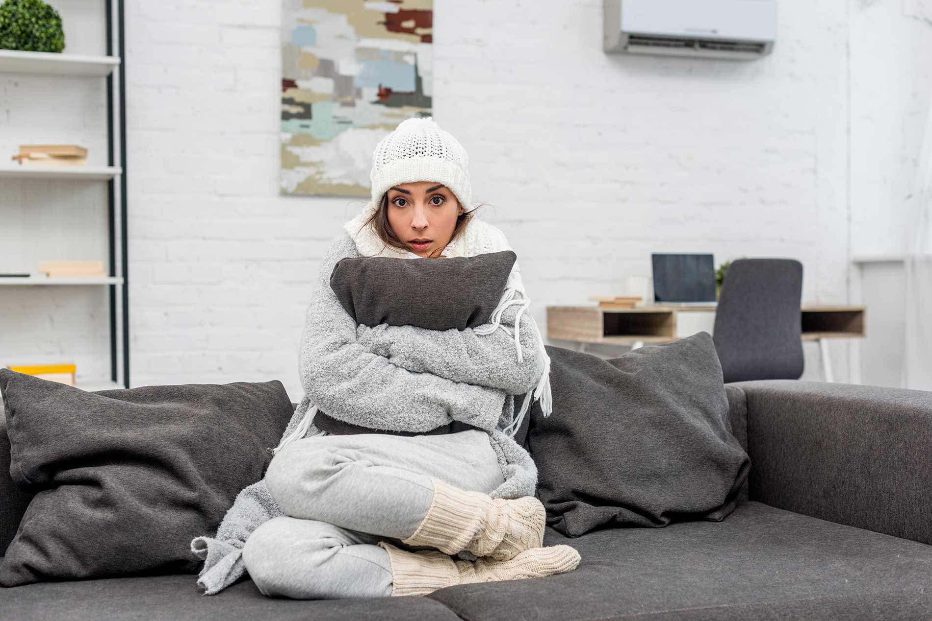woman-wearing-bundles-of-clothes-with-a-pillow-in-a-cold-room